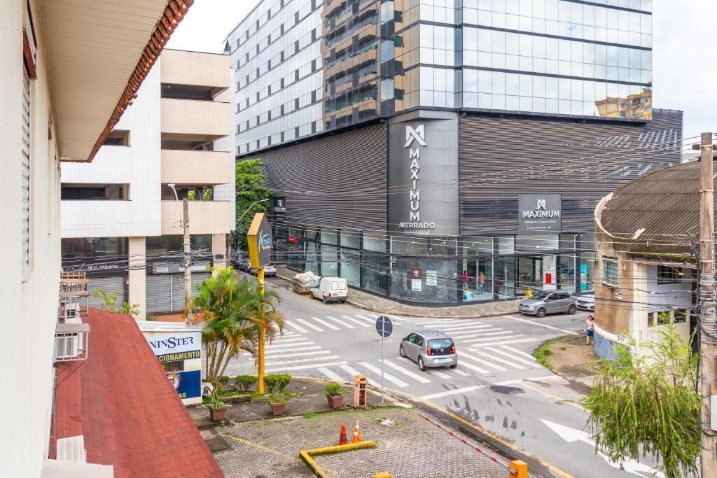 Un edificio moderno con un cartel de 'MAXIMUM', un paso de peatones y una calle con coches.