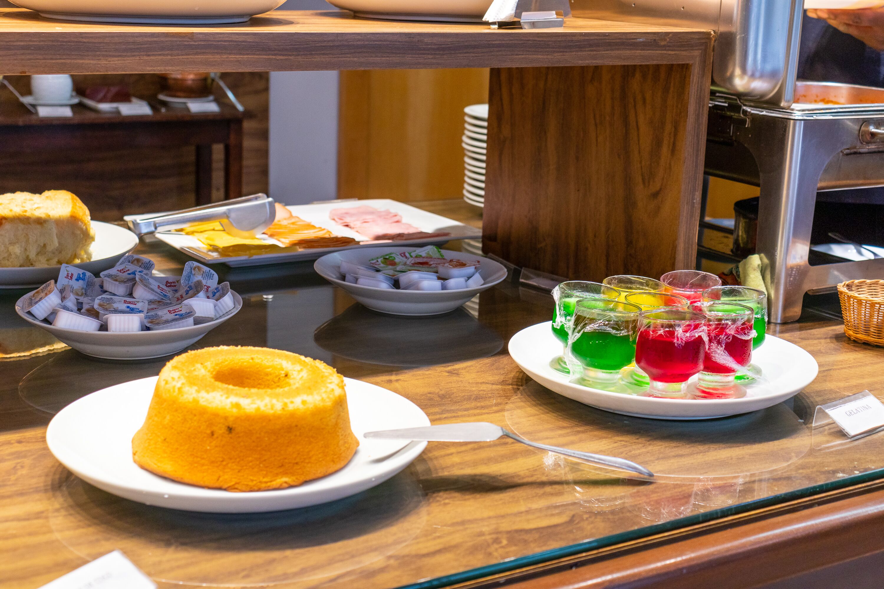 Un bufé con diversos alimentos, incluyendo un pastel bundt, pasteles y bebidas coloridas.