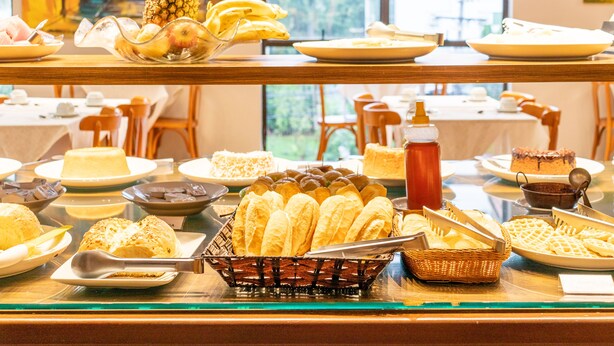 A buffet with various food items including bread, pastries, and fruits. - Dexter Hotel (Volta Redonda)