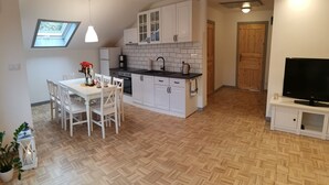 Uma cozinha moderna com armários brancos, bancada preta e piso de madeira em padrão herringbone.