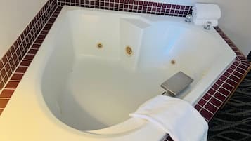 Una bañera grande y vacía con interior blanco y un revestimiento de azulejos rojos.