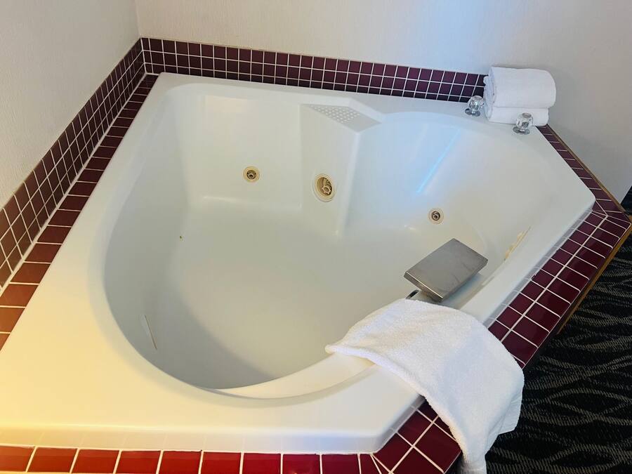 Una bañera grande y vacía con interior blanco y un revestimiento de azulejos rojos.