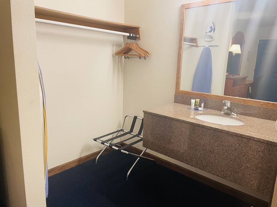 A bathroom with a sink, mirror, towel rack, and a chair.