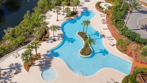 Relax by the resort's large, winding pool surrounded by lush greenery and palm trees.