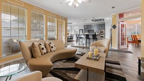Un salon moderne avec un canapé beige, une table basse en verre et un ventilateur de plafond.