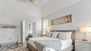 Une chambre à coucher comprenant un lit, des tables de chevet, une armoire et un ventilateur de plafond.