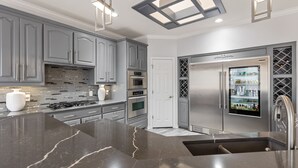 Une cuisine moderne avec des meubles gris, un réfrigérateur en acier inoxydable et un îlot central en marbre.