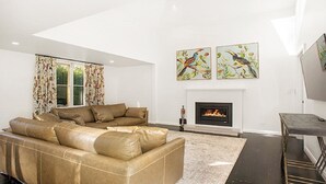 A modern living room with a leather sectional sofa, a fireplace, and two wall-mounted paintings.