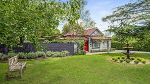 Experience a serene retreat with a traditional house, lush greenery, and a peaceful stone fountain.