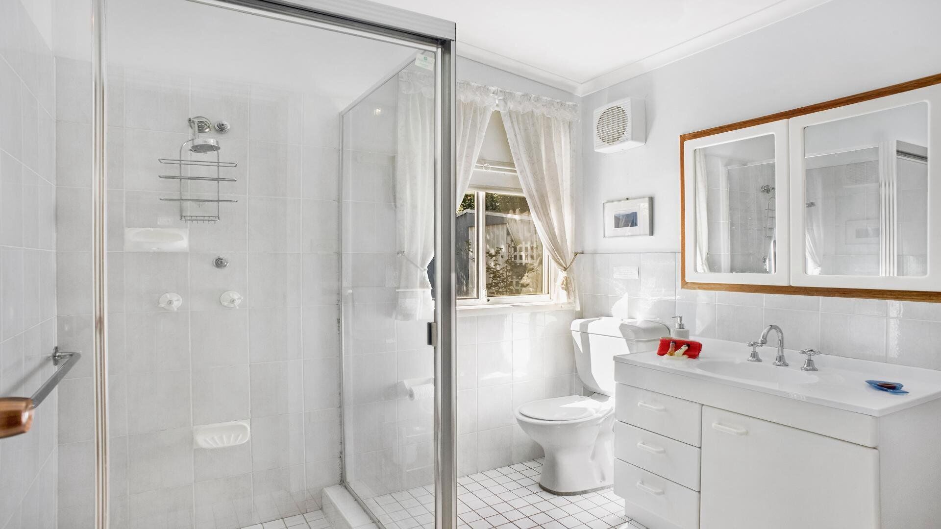 Une salle de bain moderne avec une douche à parois de verre, des toilettes et un lavabo avec un miroir au-dessus.