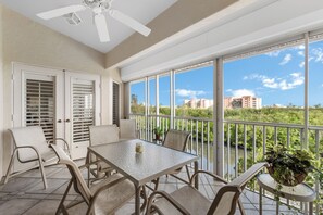 Enjoy a serene river view from this balcony with a table and chairs, ceiling fan, and railing.