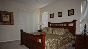 A bedroom with a wooden bed, a nightstand, a lamp, and a framed picture on the wall. - 4BR Davenport Pool Home by Watson-222CH (Davenport)