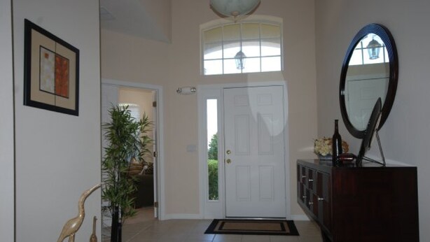 A hallway with a white door, a large mirror, and a potted plant. - 4BR Davenport Pool Home by Watson-222CH (Davenport)
