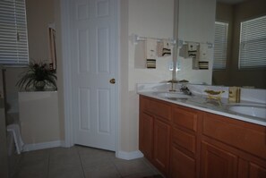 A bathroom with a double sink, wooden cabinets, a large mirror, and a potted plant. - 4BR Davenport Pool Home by Watson-222CH (Davenport)