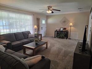 A living room with a sofa, coffee table, and a ceiling fan.