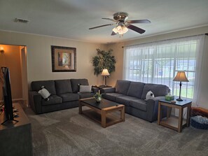 A living room with two sofas, a coffee table, a lamp, and a ceiling fan.