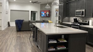 A modern kitchen with dark cabinets, a central island, and a built-in bookshelf. - Upscale Fully Renovated Biltmore Penthouse (Phoenix)