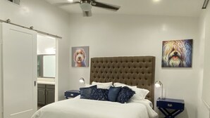 A bedroom with a tufted headboard, a large bed with white bedding, two bedside tables with lamps, and two framed pictures on the walls. - Upscale Fully Renovated Biltmore Penthouse (Phoenix)
