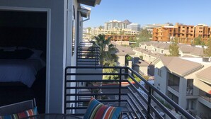 A balcony with a bed and a table, overlooking a residential area with various buildings and a clear sky. - Upscale Fully Renovated Biltmore Penthouse (Phoenix)