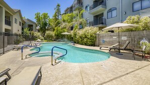 A swimming pool area with lounge chairs and umbrellas, surrounded by apartment buildings. - Upscale Fully Renovated Biltmore Penthouse (Phoenix)