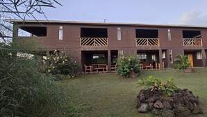 A two-story building with multiple balconies and a well-maintained garden area. - Tupuna Lodge Apartments (Hanga Roa)
