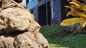 A modern house with a stone wall and a blue exterior. - Tupuna Lodge Apartments (Hanga Roa)