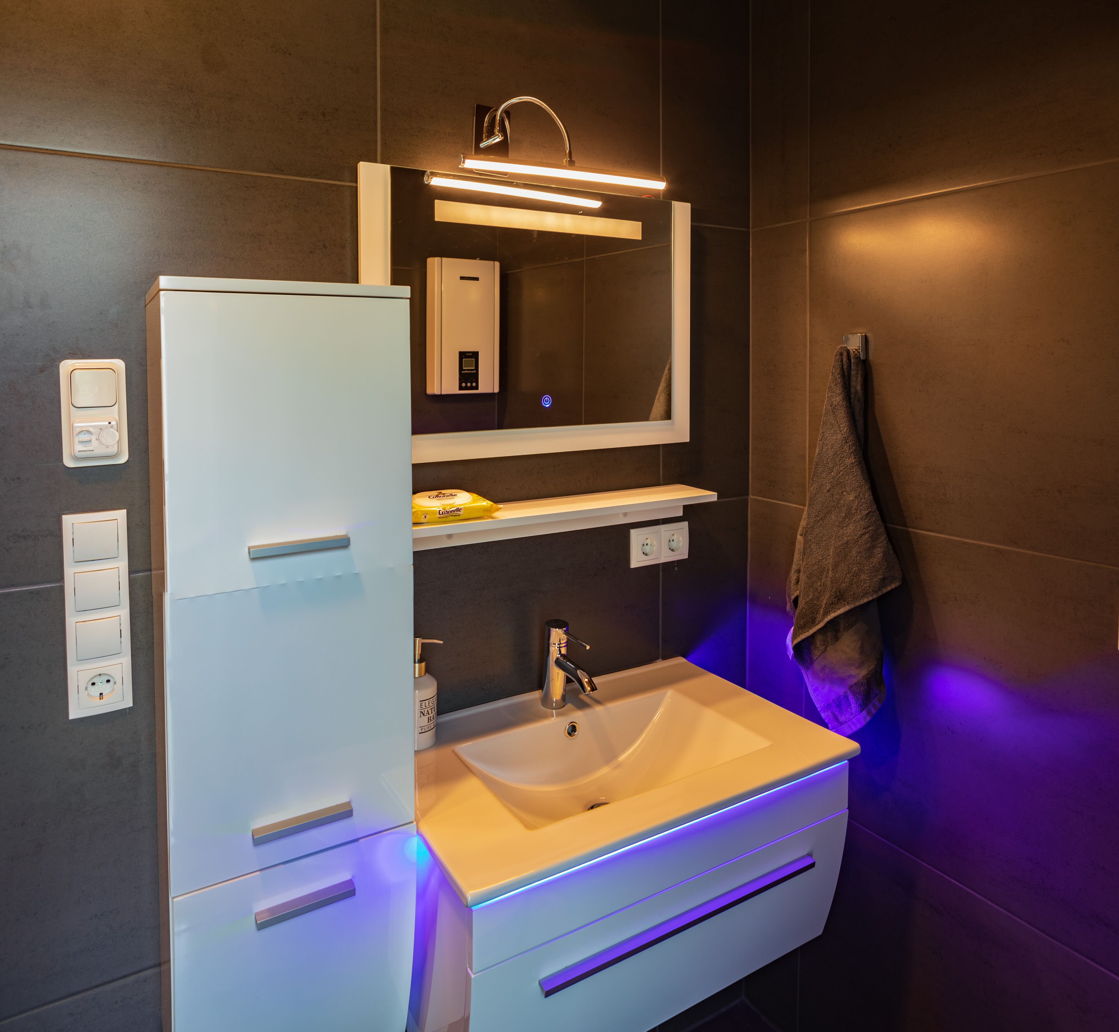A modern bathroom with a white vanity, a sink, a mirror, and a towel hanging on the wall.