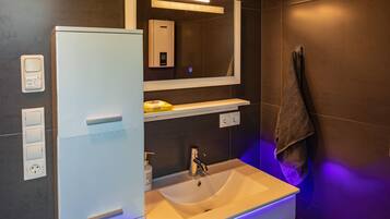 A modern bathroom with a white vanity, a sink, a mirror, and a towel hanging on the wall.