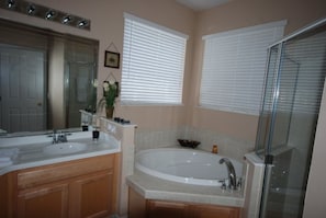 A bathroom with two sinks, a bathtub, and a glass shower enclosure.