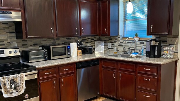 A modern kitchen with dark wood cabinets, stainless steel appliances, and a tiled backsplash. - PRIVATE DUPLEX #2 KING BED/Houston/Pasadena/ Hobby/Clear Lake/Galveston/ (Houston)