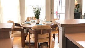A dining area with a round table, chairs, and a potted plant.