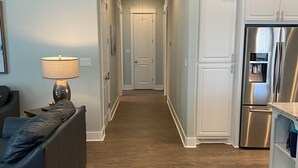A modern kitchen with stainless steel appliances, a wooden floor, and a hallway leading to a door. - Feelin’ Tip Sea - *Sleeps 10* Walking Distance to the beach! (Crystal Beach)