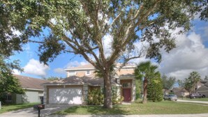 A residential house with a garage, a front yard, and a large tree. - 4BR Davenport Pool Home by Watson-767OX (Davenport)