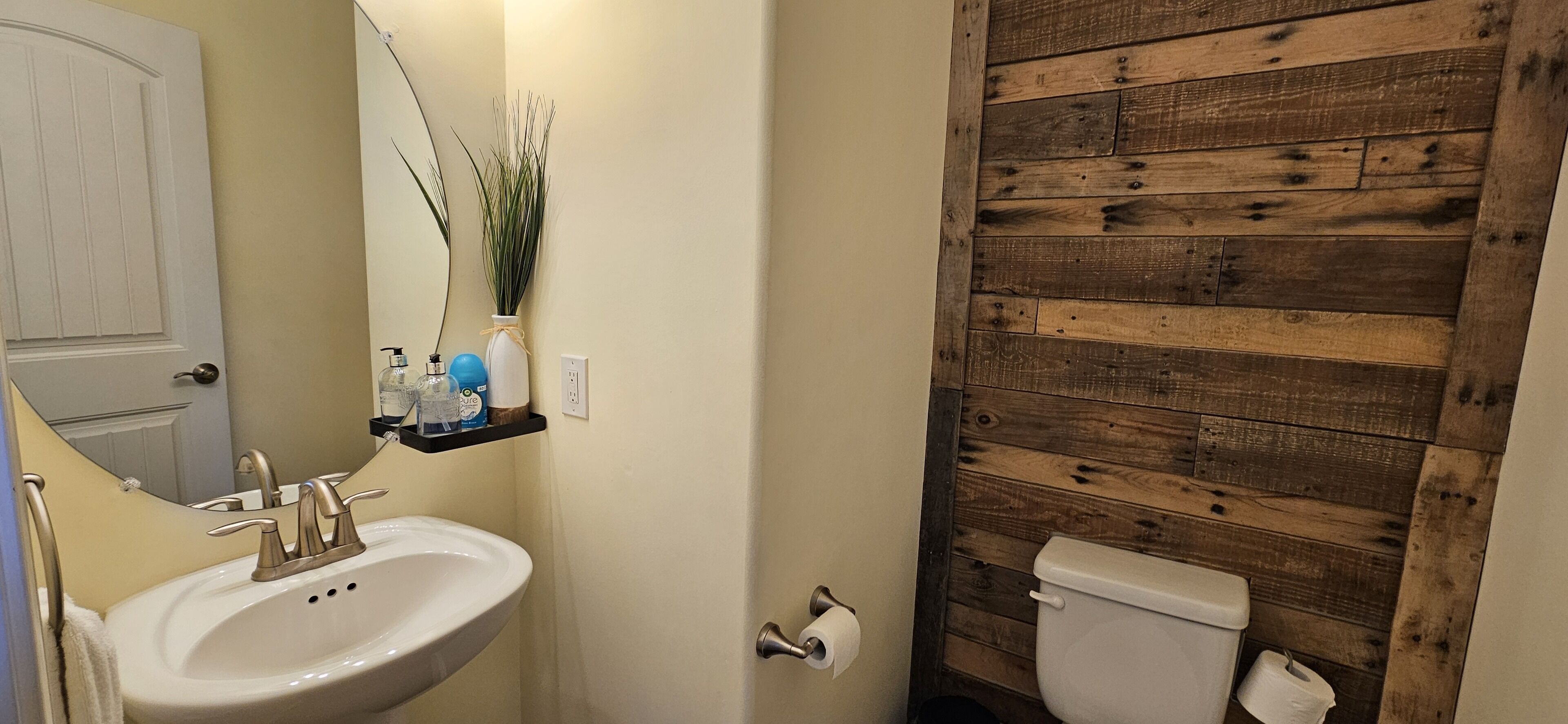 Een badkamer met een houten wand, een wastafel met spiegel en een toilet.
