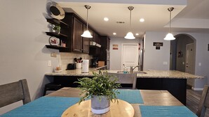 A modern kitchen with dark wooden cabinets, a granite countertop, and pendant lighting.