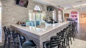 Ein moderner Barbereich mit Steinwand, einem Flachbildfernseher und einer Bar mit Hockern.