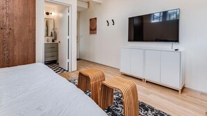 Une chambre moderne avec un grand lit, un téléviseur fixé au mur et une commode blanche en dessous.