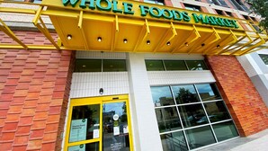 Un magasin Whole Foods Market avec un auvent jaune et de grandes fenêtres.