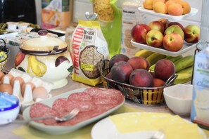 A table with various food items including eggs, sausages, fruits, and a bag of flour. - Villa Gelsomino Garden (Florence)