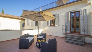 Un patio al aire libre con muebles de mimbre, una mesa y un cuenco de fruta.