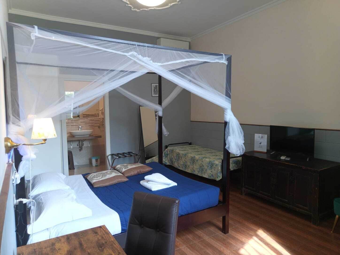 Ein Hotelzimmer mit Himmelbett, Fernseher, Holztisch und Stuhl.