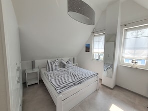 Makuuhuone, jossa on sänky, yöpöydät, ikkuna, josta on näkymä, ja kattovalaisin.