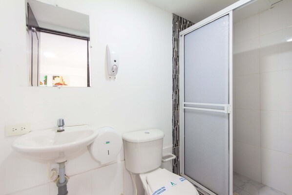Baño con lavamanos blanco, inodoro y cabina de ducha.
