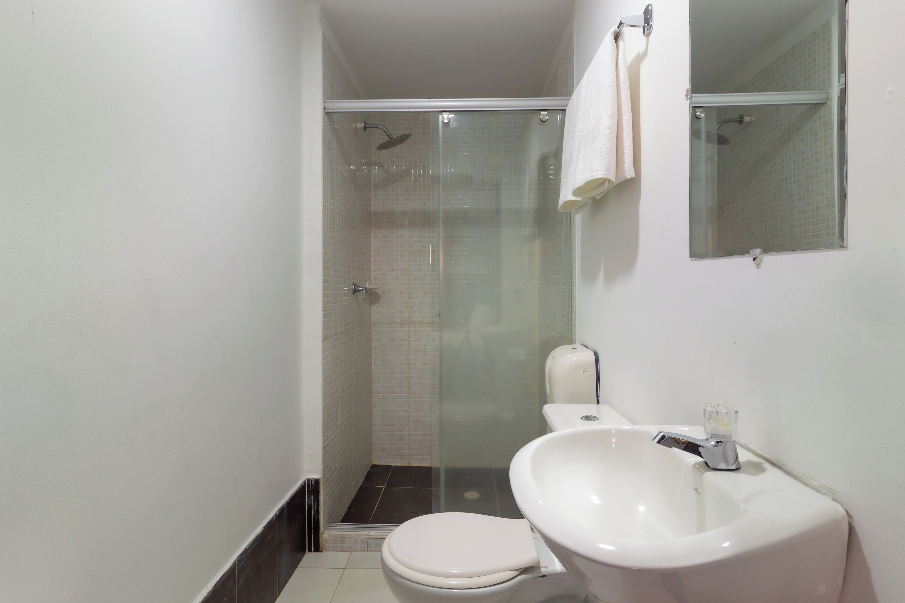 A compact bathroom with a toilet, sink, and glass-enclosed shower.