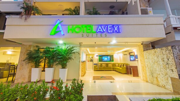 A hotel entrance with a reception desk, a TV screen, and a seating area. - Hotel Avexi Suites By Geh Suites (Cartagena)