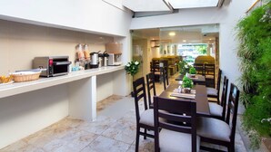 A compact kitchen with a microwave, toaster, and coffee maker, a dining area with a table and chairs, and a view into the dining room. - Hotel Avexi Suites By Geh Suites (Cartagena)