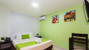 A hotel room with a bed, a chair, a desk, and a TV. - Hotel Avexi Suites By Geh Suites (Cartagena)