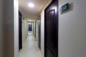 Un pasillo de hotel con puertas numeradas 113, 114 y 115.
