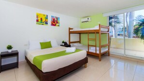 A hotel room with a bunk bed, a single bed, a green throw blanket, a small plant, and colorful artwork on the wall. - Hotel Avexi Suites By Geh Suites (Cartagena)