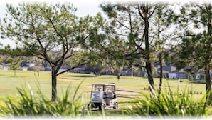 A golf cart on a golf course with trees and houses in the background. - 5BR Davenport Pool Home by Watson-465GE (Davenport)